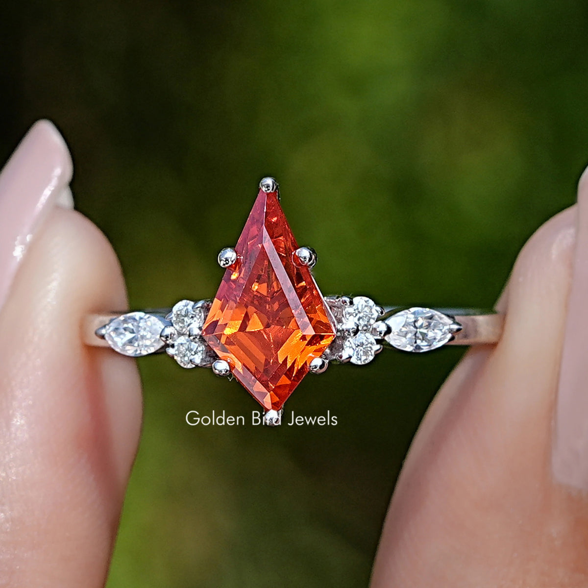 Front view of Orange Kite Cut Gemstone Accent Ring in two fingers 