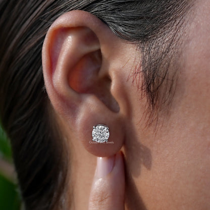 Round-cut solitaire stud earring worn on ear with clear stone and silver-toned bezel