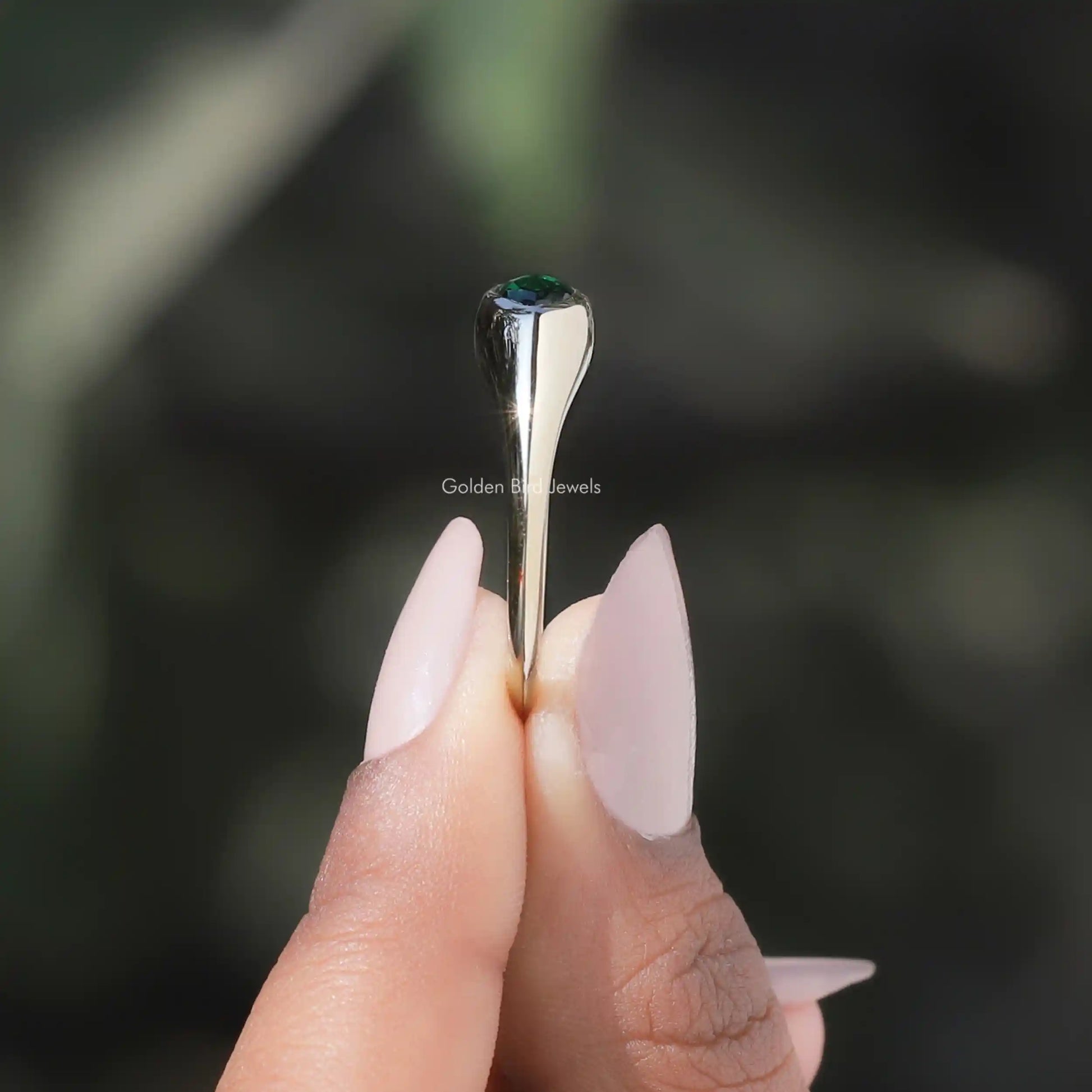 Side View of Bezel Set Marquise Cut Solitaire Engagement Ring In two fingers