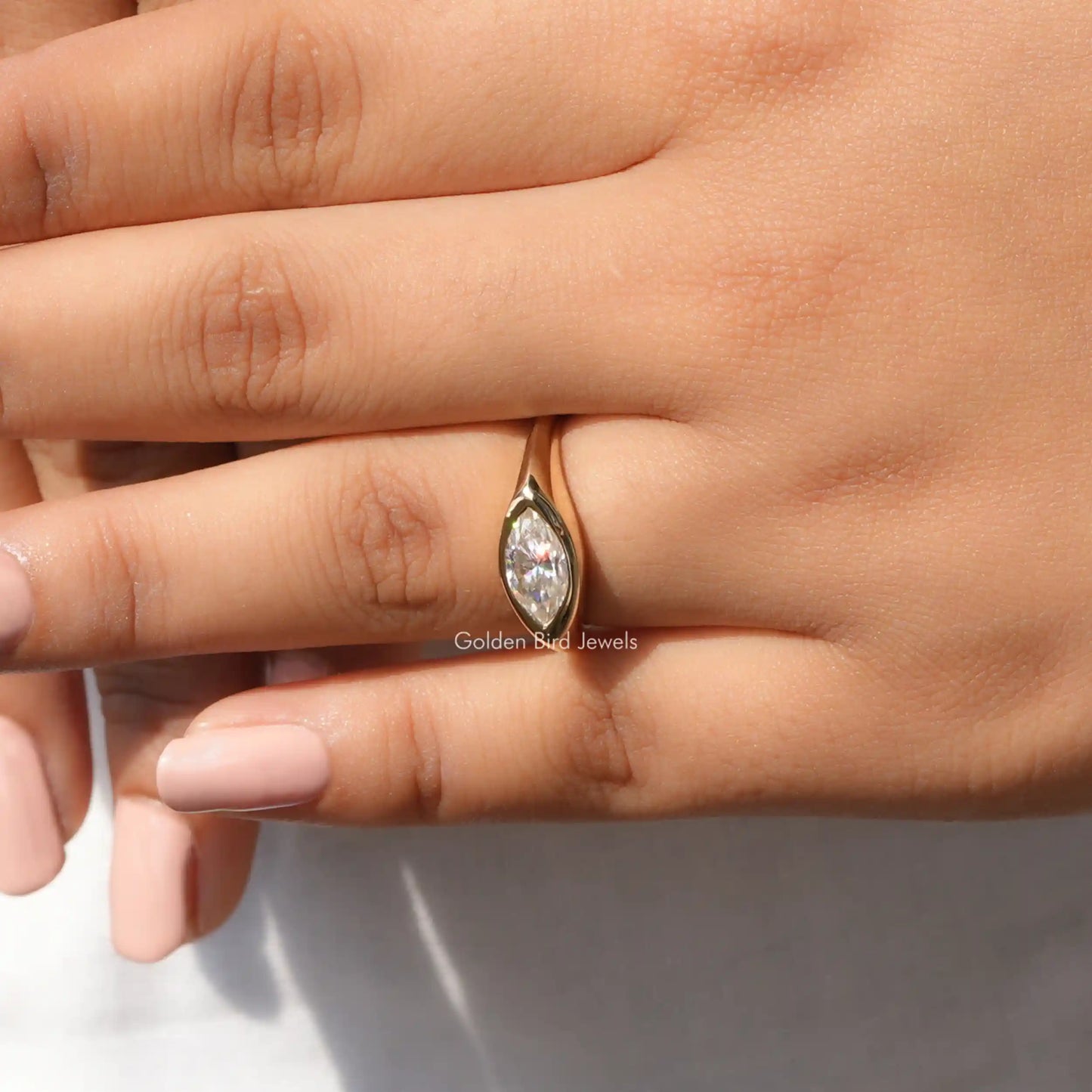 In finger front view of halo moissanite engagement ring in yellow gold 