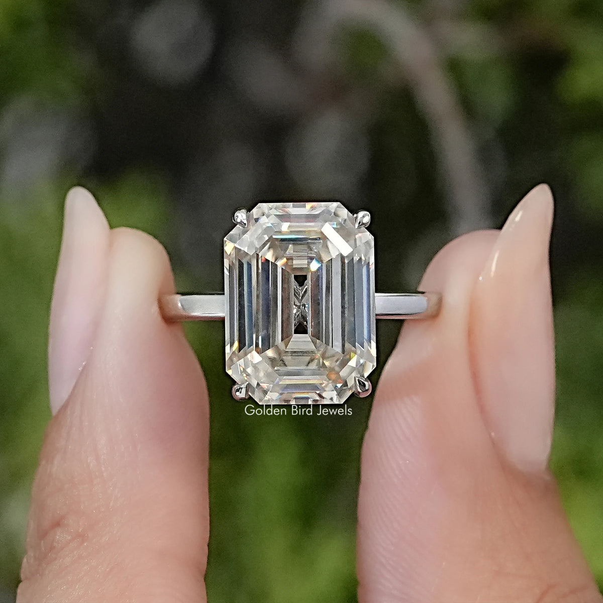 Emerald-cut moissanite engagement ring with a large clear center stone and slim silver band