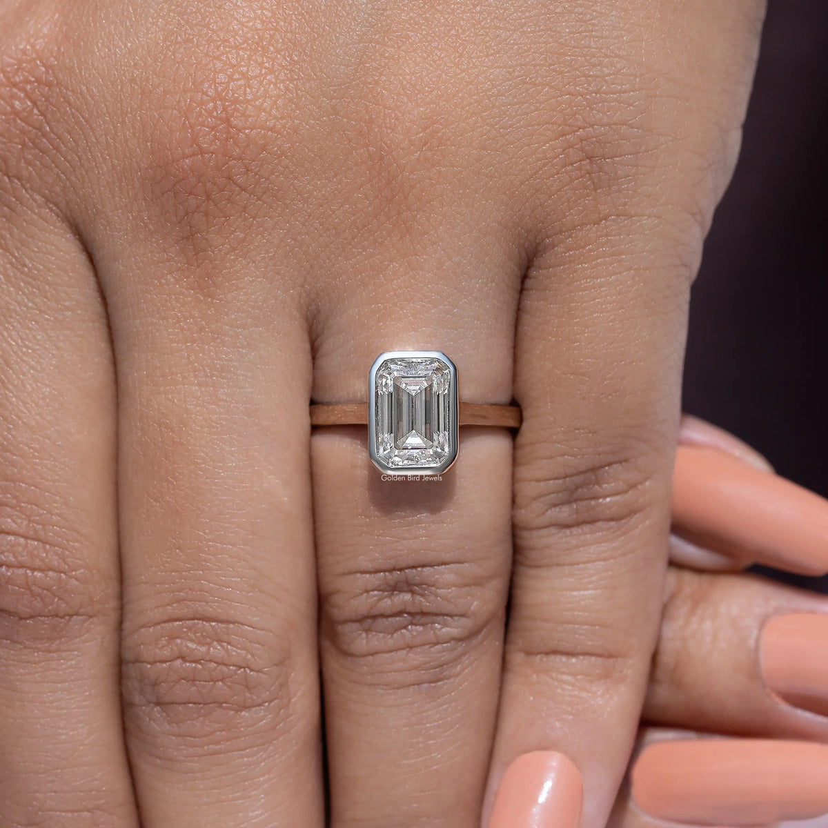 Emerald-cut moissanite solitaire ring with bezel setting and slim metal band