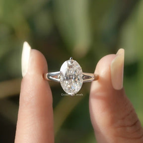 Two fingers holding the Moissanite Crushed Ice Oval Hidden Halo Ring