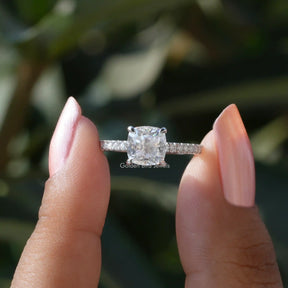 Front View of Cushion Cut Solitaire Accent Engagement Ring In two Fingers