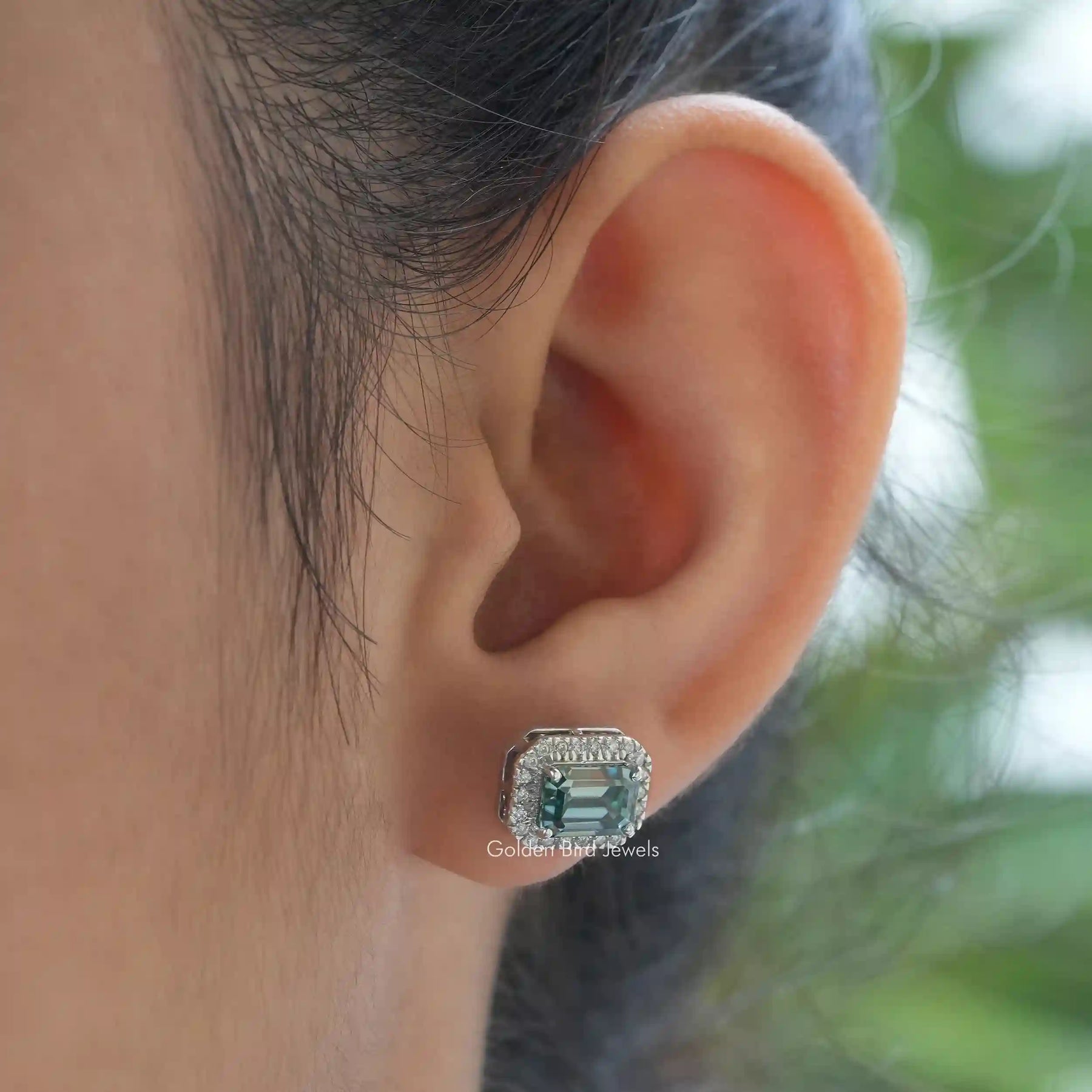 [In ear front view of green emerald cut moissanite stud earrings]-[Golden Bird Jewels]