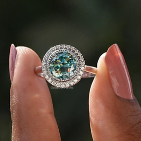 Two fingers holding the Old European Round Moissanite Halo Ring
