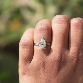In finger front view of halo old mine pear moissanite engagement ring