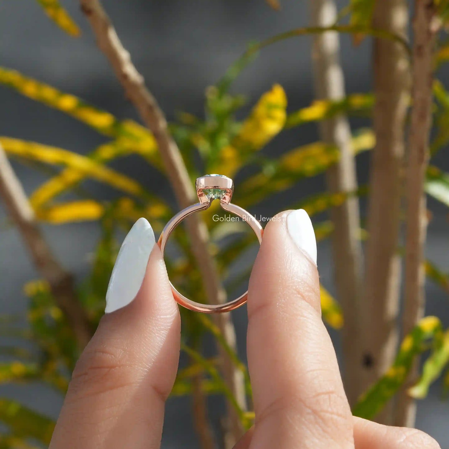 Back View of Rose Gold Moissanite Pear Cut V Prong Ring In two fingers