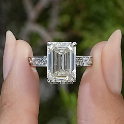 Sterling silver solitaire ring with a rectangular emerald-cut clear center stone and engraved shoulders