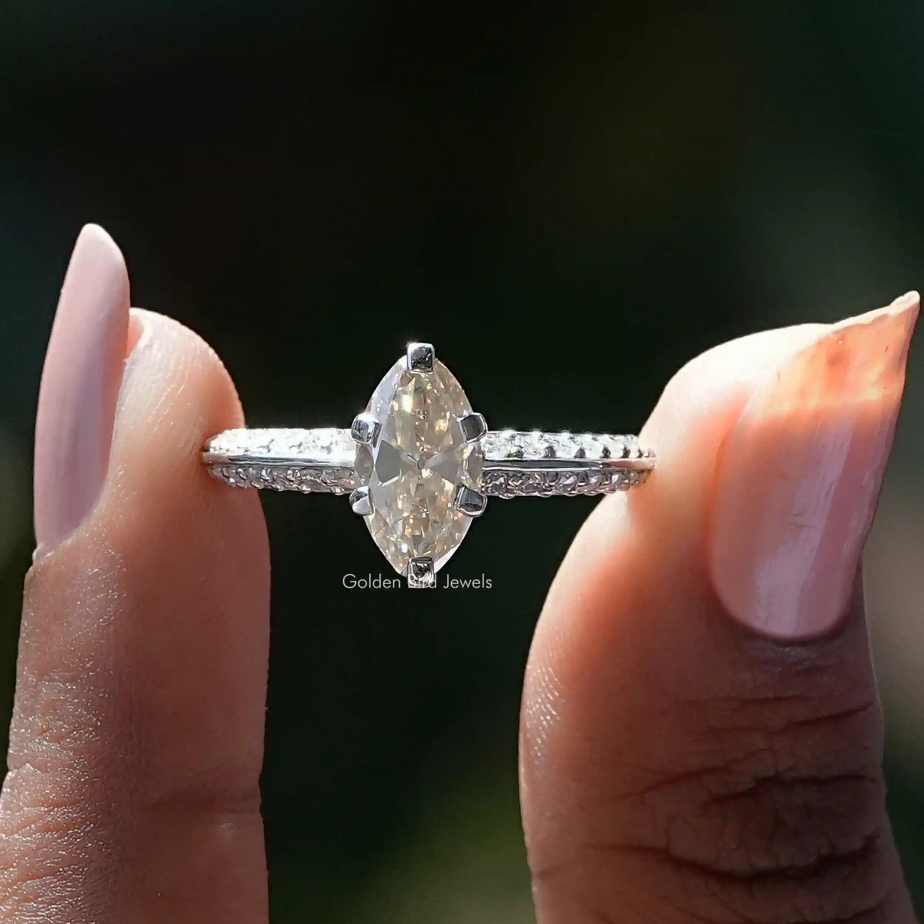 Two fingers holding the Moval Cut Moissanite Accent Ring