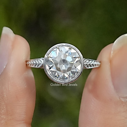 Sterling silver moissanite solitaire ring with a round bezel-set stone and detailed shoulders