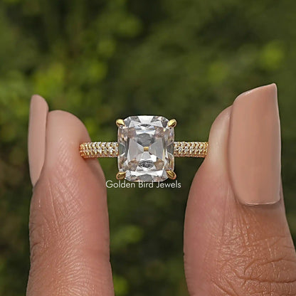 Cushion-cut moissanite solitaire ring with prong-set center and pave gold-tone band