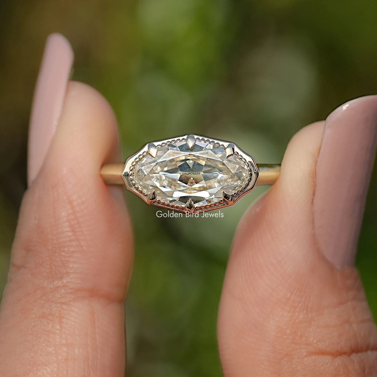 Gold-tone oval solitaire ring with raised bezel setting and faceted center stone