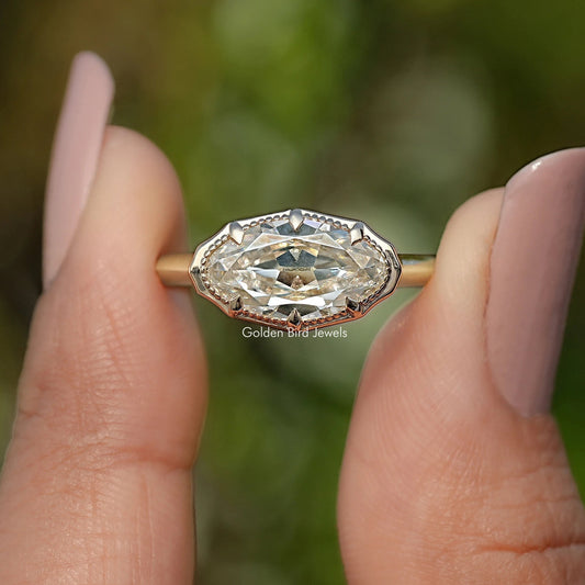 Gold-tone oval solitaire ring with raised bezel setting and faceted center stone