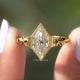 Two fingers holding the old mine dutch marquise cut moissanite ring