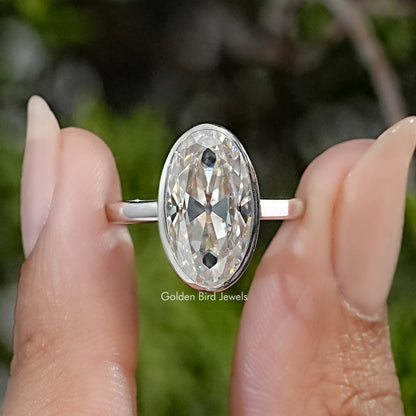Sterling silver solitaire ring with an elongated oval moissanite in a bezel setting.