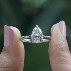 Two fingers holding the Old Mine Pear Cut Moissanite Engagement Ring