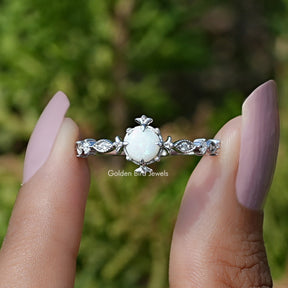 Two fingers holding the Opal Round Gemstone Accent Engagement Ring