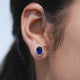 Close-up of an ear wearing a blue gemstone earring with a blurred background