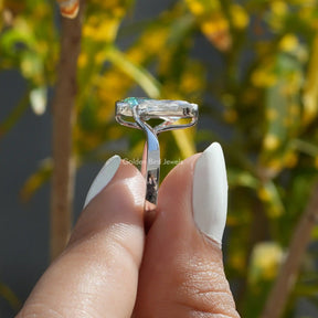 Close up view  of a women’s halo engagement ring holding  on two fingers 