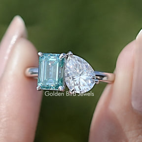 Front view of Pear And Emerald Cut Two Stone Moissanite Ring in two fingers 