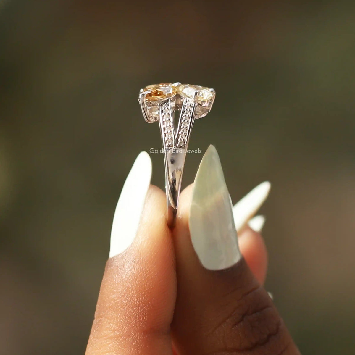 Side View of Pear And Round Cut Engagement Ring In two fingers