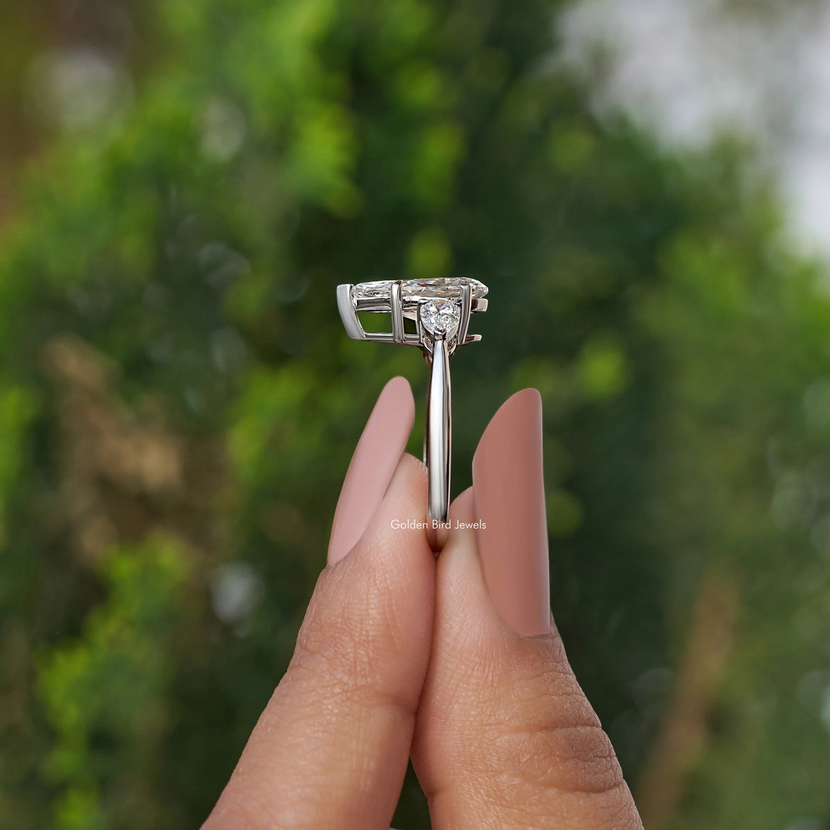 Side View of 3 Stone Pear Cut Diamond Engagement Ring In two fingers