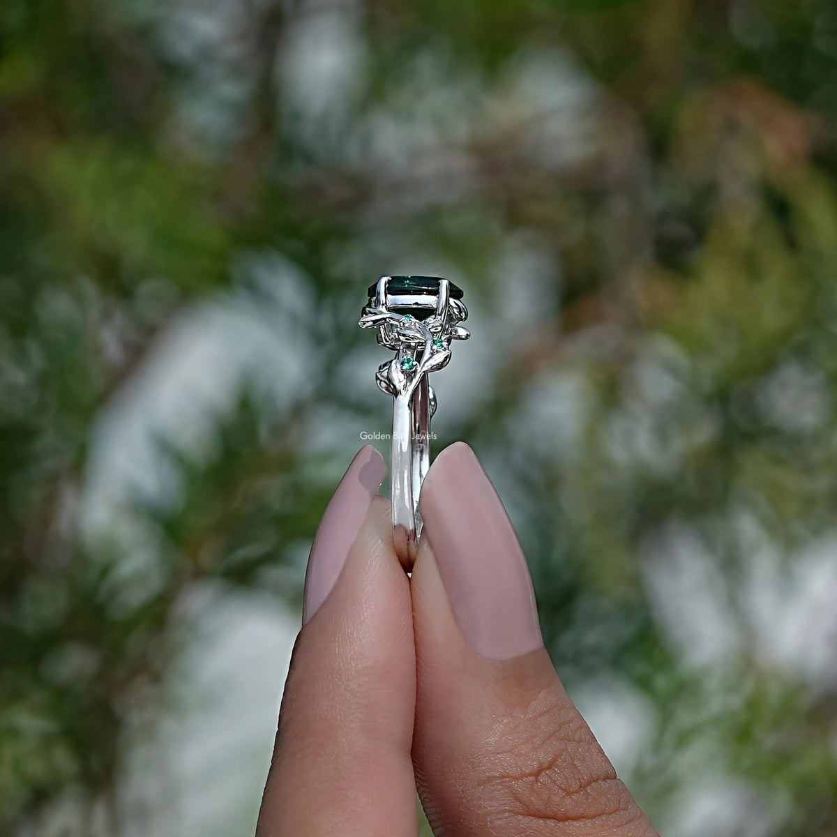 Side View of Green Oval Cut Engagement Ring In two fingers