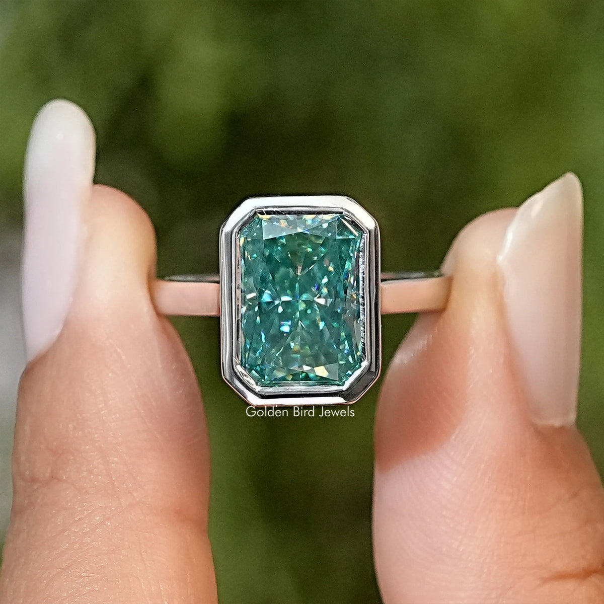 Teal moissanite bezel-set solitaire ring with emerald-cut center stone