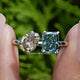 Front view of Radiant And Pear Toi Et Moi Moissanite Ring in two fingers 