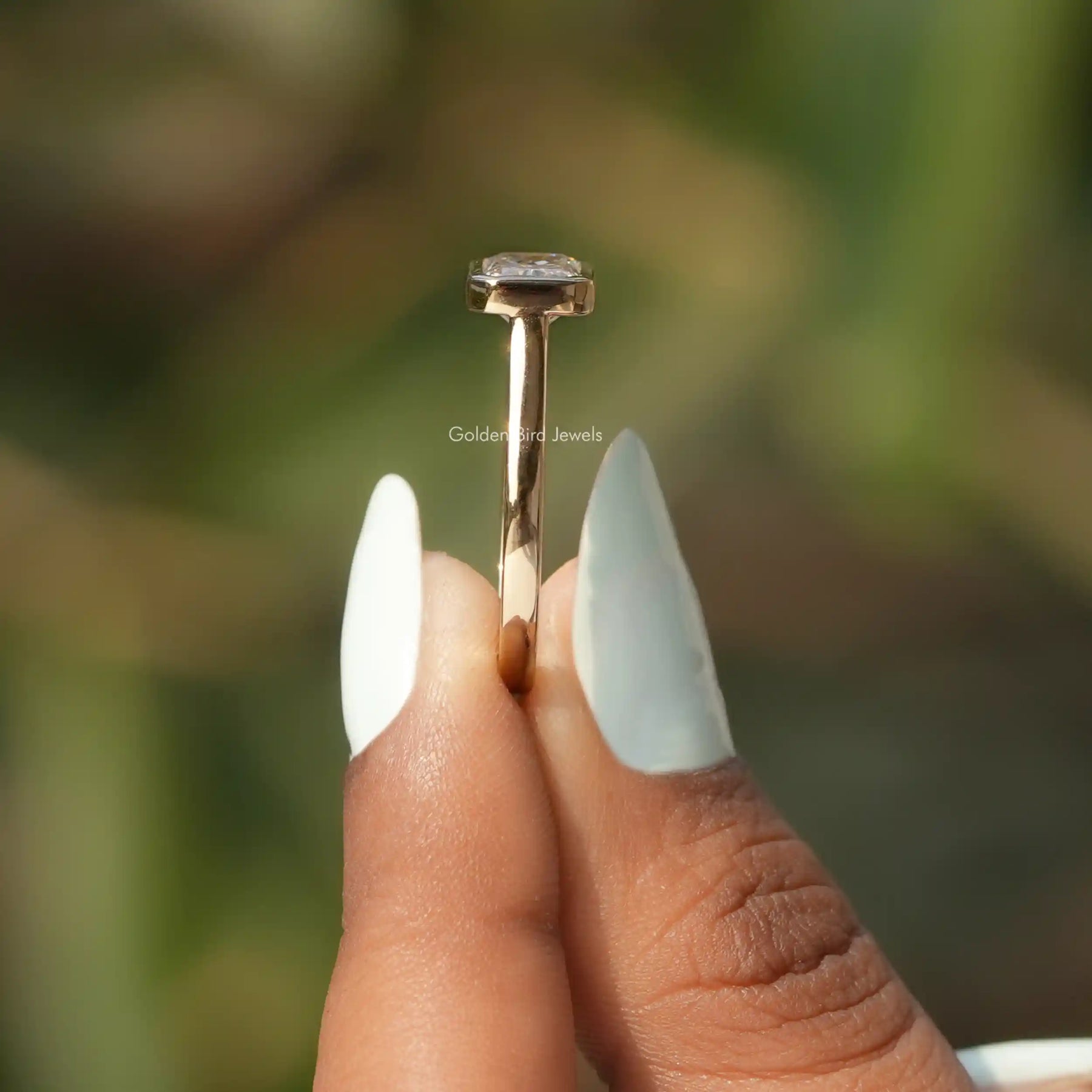 Side View of Radiant Cut Solitaire Engagement Ring In two fingers