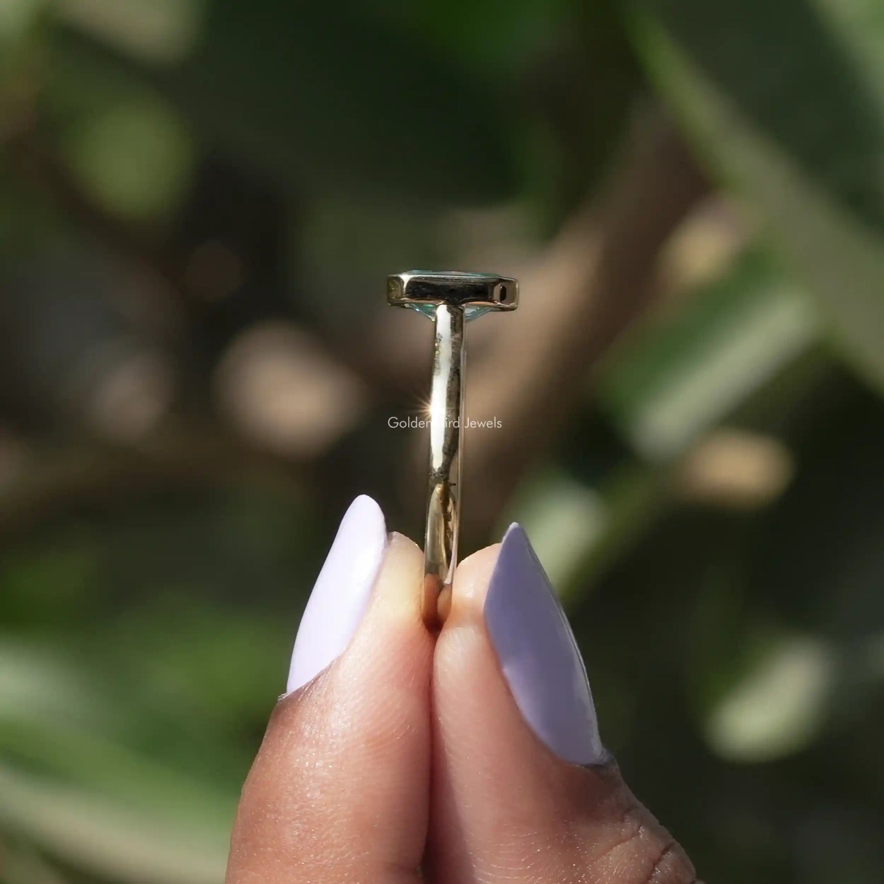 Side View of Radiant Cut Moissanite Bezel Set Ring In two fingers