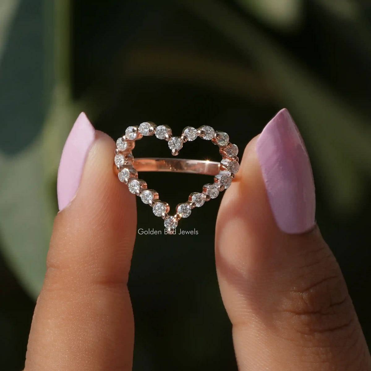 Two fingers holding the Round Cut Moissanite Heart Shaped Ring