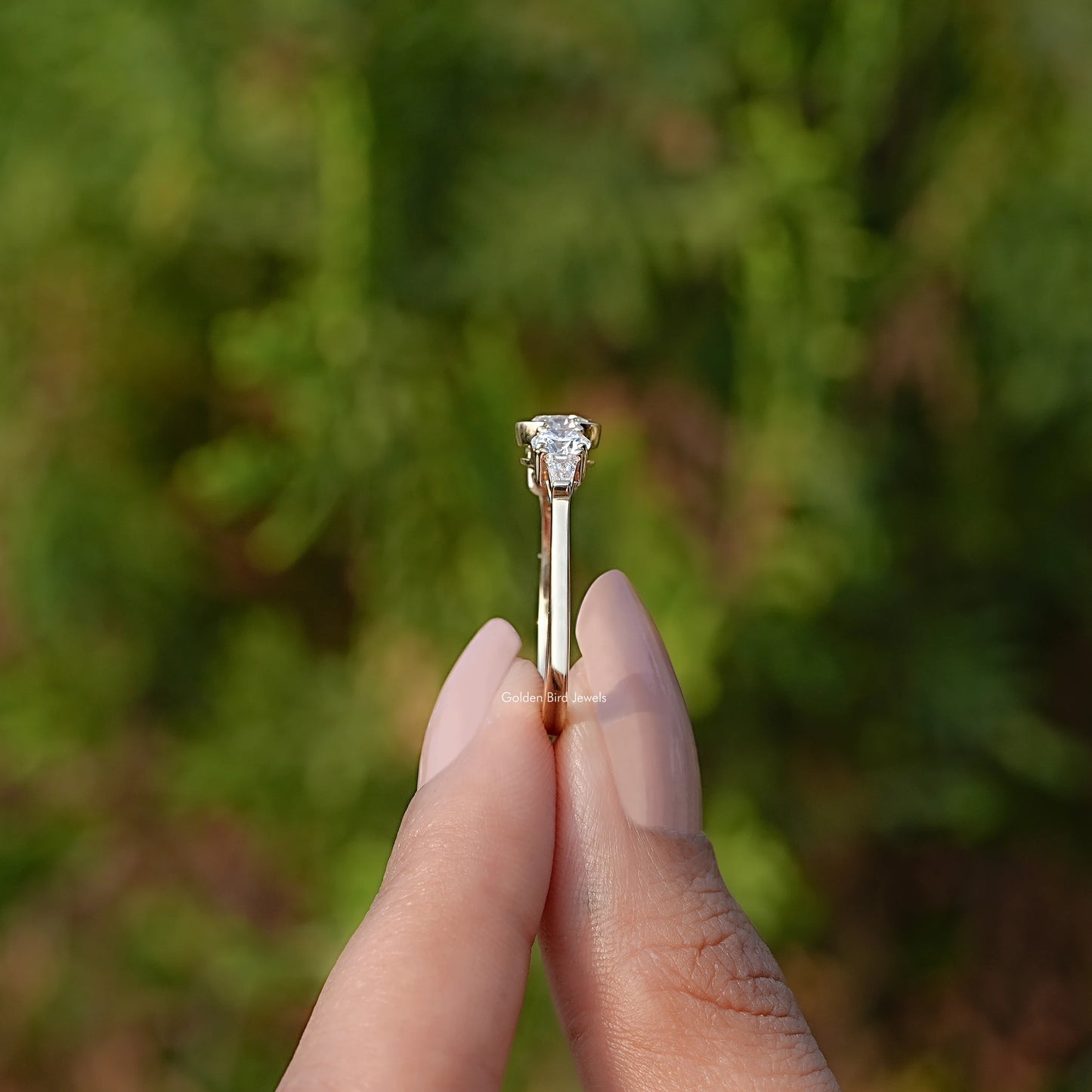 Side View of Round Cut Diamond Engagement Ring In two fingers