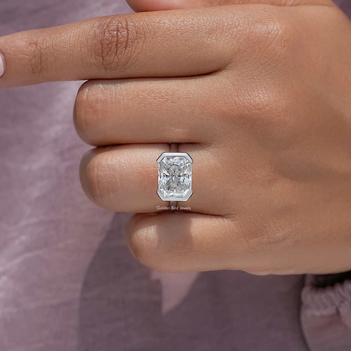 Close-up of radiant-cut center stone set in a silver half-bezel solitaire ring