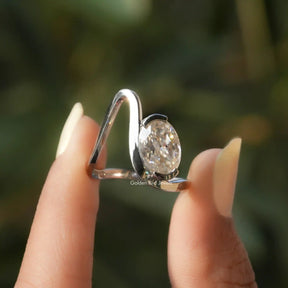 Two fingers holding the Solitaire Oval Cut Moissanite Curved Ring