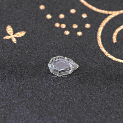 Faceted clear step-cut moissanite loose gemstone, side view on dark fabric.