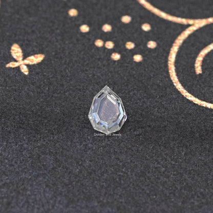 Faceted clear moissanite loose gemstone with visible step facets, on dark fabric.