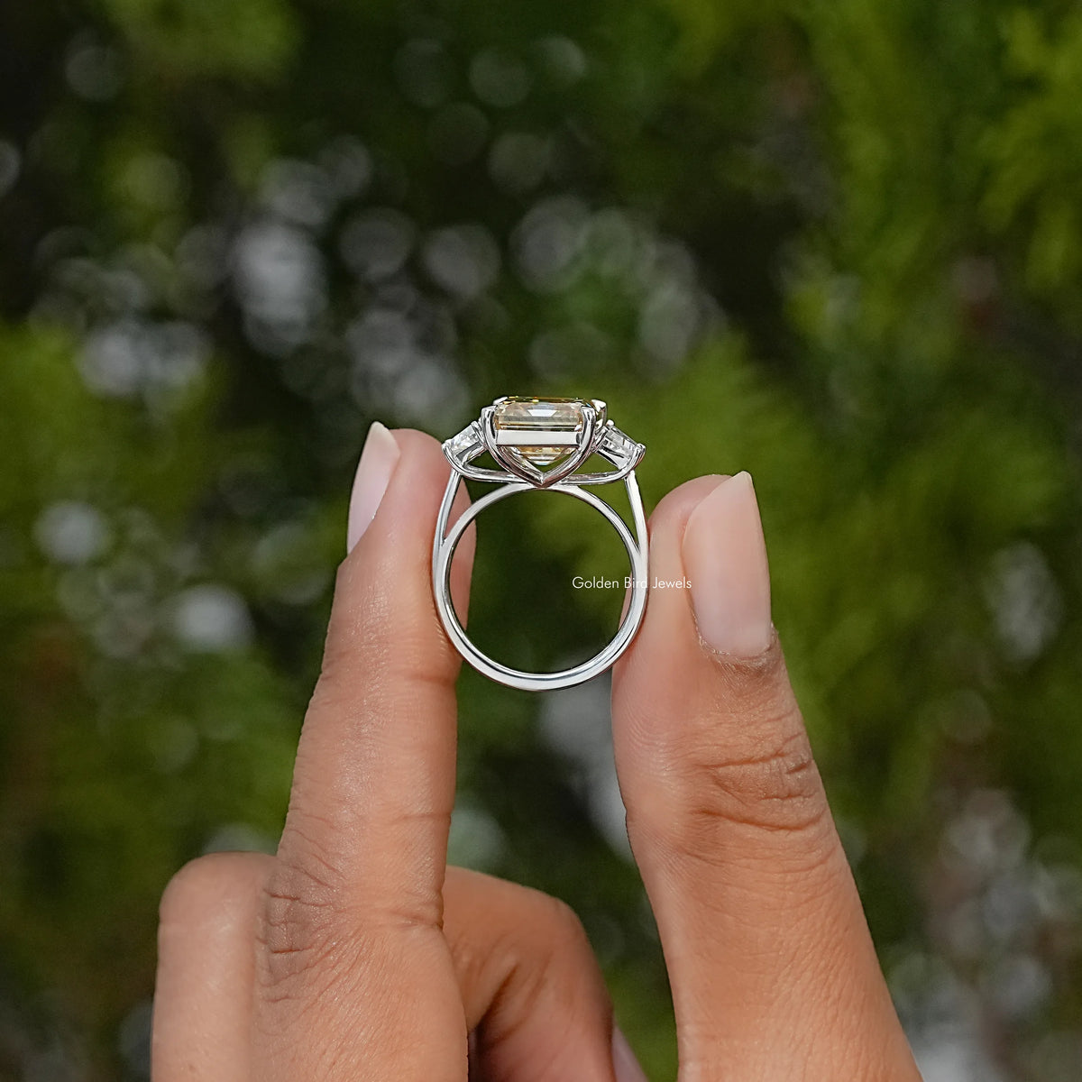 Side view of a sterling silver engagement ring showing its raised Asscher-cut center stone and setting